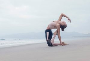 Female performs yoga on the beach